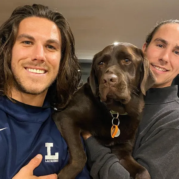 Callum and Jake smiling and holding a dog.
