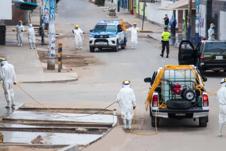 Workers in protective gear sanitize streets