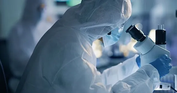 Scientist, chemist or engineer analysing the cure for covid in a laboratory using a microscope. Researching a virus and finding a cure through science